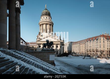 Gendarmenmarkt in Berlin mit französischem Dom. Das Bild wurde von den Stufen des Konzertsaals an einem hellen Wintertag mit blauem Himmel und Schnee aufgenommen. Stockfoto