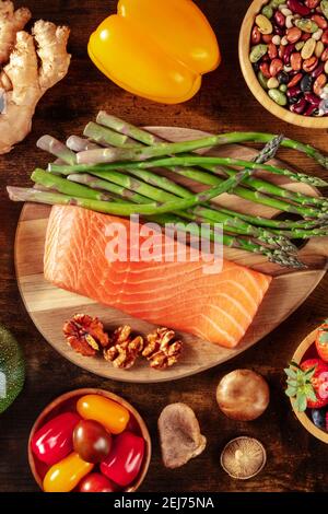 Gesunde Ernährung. Lachs, Spargel und andere Superfoods, von oben auf einem dunklen rustikalen Holzhintergrund geschossen Stockfoto