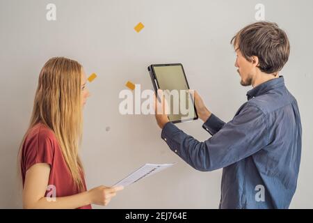 Der makler überprüft den Zustand der Wohnung, wenn die Mieter sind im Begriff, auszuziehen. Die Wände waren beschädigt, man muss dafür bezahlen oder abziehen Stockfoto