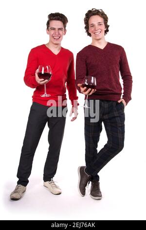 Feiertage und Wochenenden. Junges attraktives Paar trinkt Rotwein. Weißer Hintergrund. Stockfoto