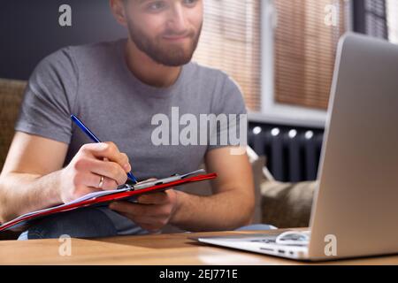 Zugeschnittenes Foto eines jungen Studenten, der online vor dem Laptop zu Hause studiert. Das Konzept des Lernens während einer Pandemie und maximale Verantwortung auf dem Stockfoto