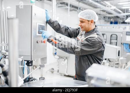 Werksingenieur Mann Bedienmaschine Bedienfeld in Molkereimilchproduktionsanlage. Stockfoto