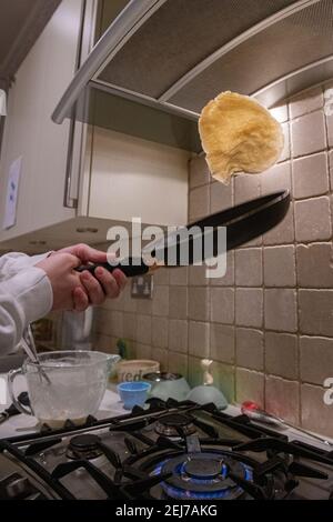 Ein Teenager wirft einen Pfannkuchen am Pfannkuchen-Tag, Faschingsdienstag Stockfoto