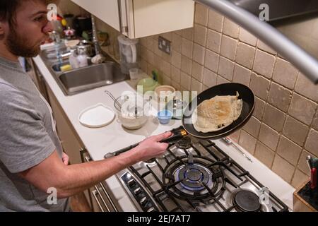 Ein Teenager wirft einen Pfannkuchen am Pfannkuchen-Tag, Faschingsdienstag Stockfoto