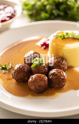 Teller mit schwedischen Fleischbällchen in Sauce mit Kartoffelpüree und Preiselbeersoße. Stockfoto