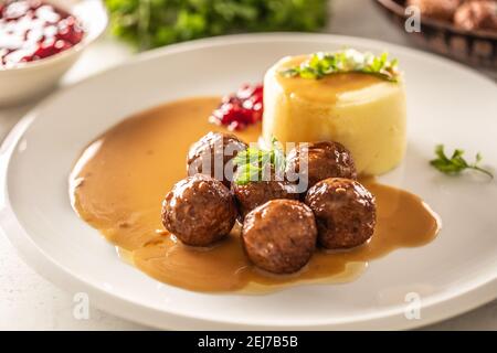 Teller mit schwedischen Fleischbällchen in Sauce mit Kartoffelpüree und Preiselbeersoße. Stockfoto