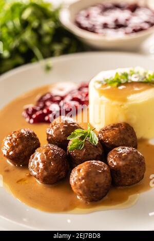 Teller mit schwedischen Fleischbällchen in Sauce mit Kartoffelpüree und Preiselbeersoße. Stockfoto