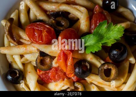 Fusilli al Ferro mit schwarzen Oliven und Kirschtomaten Stockfoto