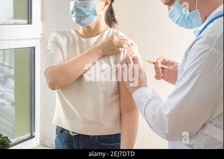 Impfstoffinjektion covid19. Arzt Hält Spritze Und Macht Injektion An Senior Patient In Medizinische Maske. Covid-19 Impfkonzept Stockfoto