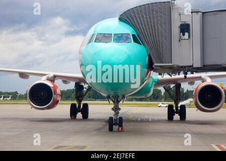 Passagiere im Flugzeug durch die Bordbrücke besteigen. Das Flugzeug landet auf dem internationalen Flughafen. Gepäck wird geladen. Blaues Flugzeug. Klemme R Stockfoto