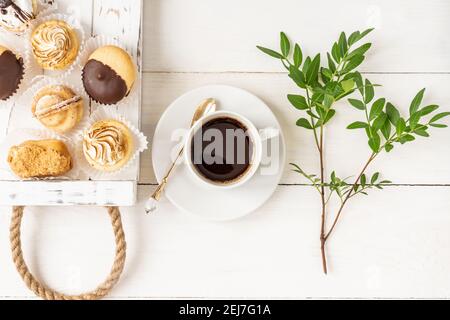 Frühstück im Bett. Tasse Kaffee und frische leckere Mini-Desserts auf einem Holztablett. Stilvolle Inneneinrichtung. Flach liegend, Draufsicht Stockfoto