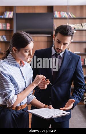 Multiethnische Geschäftsleute, die einen Vertrag halten und im Restaurant Stift halten Stockfoto