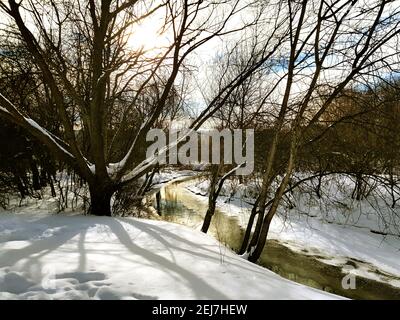 Handy-Foto. Ein ungroßer Bach inmitten von schneebedeckten Ufern. Stockfoto