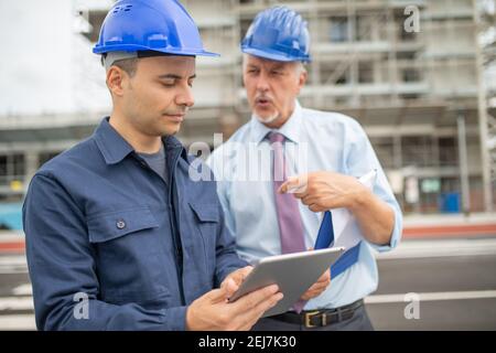 Zwei Architektenentwickler überprüfen Baupläne auf der Baustelle mit Ein Tablet Stockfoto