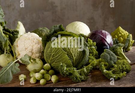 Verschiedene Arten von reifen gesunden Kohl auf rustikalem Holz angeordnet Tisch im Studio Stockfoto