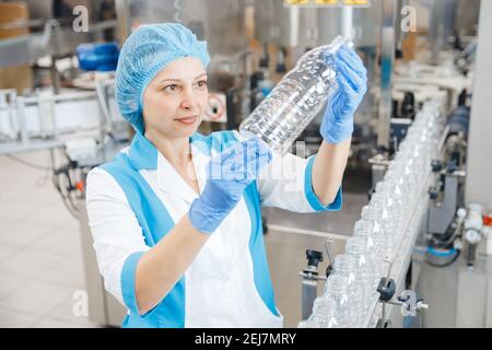 Arbeiter weiblich Überprüfung Produktionslinie Fabrik Milch Getränke in Plastikflasche. Stockfoto