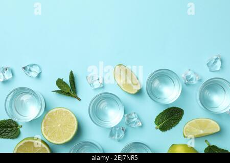 Schüsse, Limettenscheiben, Minze und Eiswürfel auf blauem Hintergrund, Draufsicht Stockfoto