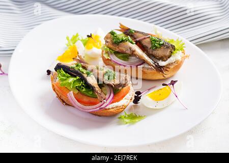 Sandwich - Smorrebrod mit Sprossen, Avocado, Tomaten, Eiern und Frischkäse auf weißem Teller. Dänische Küche. Umweltfreundliches Konzept. Stockfoto