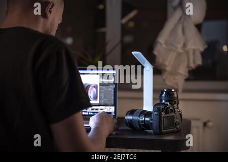 Der Fotograf arbeitet an einem Laptop, seine Kamera ist in der Nähe. Das Konzept der professionellen Arbeit mit Foto und Video. Stockfoto