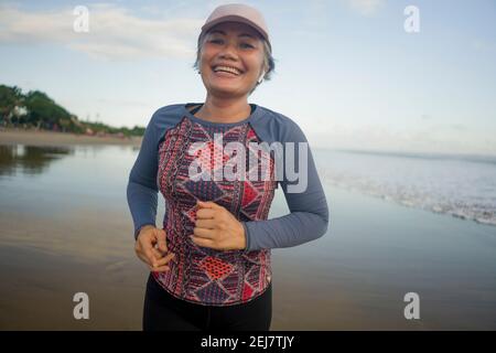 Fit und attraktive reife Frau mit grauen Haaren tun Strand Workout auf ihr 50s Laufen am Strand glücklich und Kostenlos im Senior Fitness Selfcare und welln Stockfoto