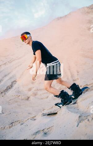 Extremer Absand auf Snowboard in der Wüste. Männlicher Snowboarder auf Dünen. Stockfoto