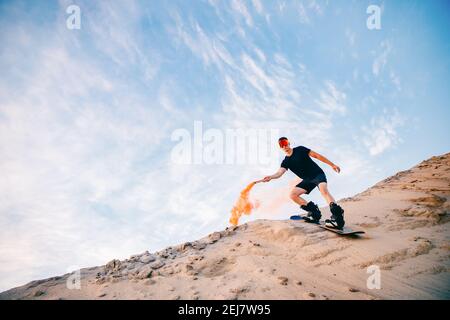 Extremer Absand auf Snowboard in der Wüste. Männlicher Snowboarder auf Dünen. Stockfoto