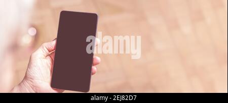 Ältere Frauen Hand halten Handy. Über der Schulter. Alte Frau, die auf das Handy schaut. Banner. Blanck Handy-Bildschirm. Anzeigemedien. Stockfoto