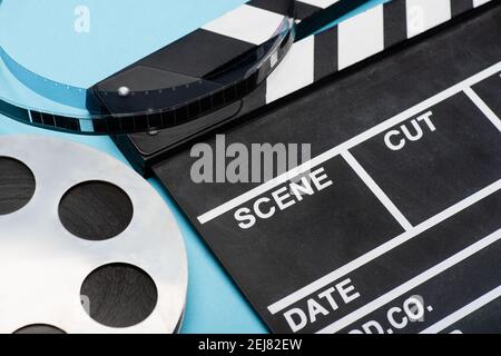 Nahaufnahme des Klappbretts und der Filmspule auf blauem Kinokonzept Stockfoto