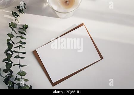 Leere Papierkarte und Eukalyptuszweige auf dem weißen Tisch. Stockfoto