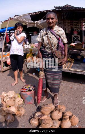 Alte Frau mit Regenschirm, der Kokosnüsse verkauft, Markt, Kalabahi, Alor, East Nusa Tenggara Province, Indonesien, Asien Stockfoto