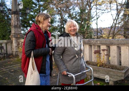 Ältere Frau mit Gehrahmen und Betreuer im Freien in der Stadt, Einkaufen und Coronavirus Konzept. Stockfoto