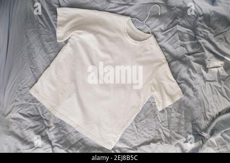 Weißes Baumwoll-T-Shirt auf dem Bett Stockfoto