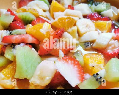 Schüssel mit frischem Obstsalat umgeben von einer Auswahl frisch zubereiteter Früchte. Stockfoto