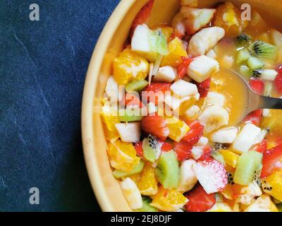 Schüssel mit frischem Obstsalat umgeben von einer Auswahl frisch zubereiteter Früchte. Stockfoto