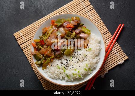 Gekochter weißer Reis mit gebratenem Gemüse (Zwiebel, Karotte, grüne Erbsen, Mais, Bohnen) in einer weißen Schüssel gemischt Stockfoto