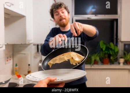 Junger Mann macht Pfannkuchen am Faschingsdienstag, 2021 Stockfoto