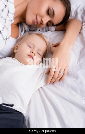 Blick von oben auf die junge Mutter, die in der Nähe des kleinen Sohnes schläft Zu Hause