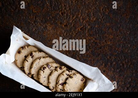 Vanille- und Schokoladenkekse in einer Holzkiste mit weißem Backpapier, auf dunklem Hintergrund. Stockfoto