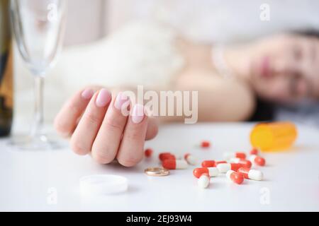 Braut im Hochzeitskleid liegend auf Couch mit Handvoll Pillen in der Hand Nahaufnahme Stockfoto