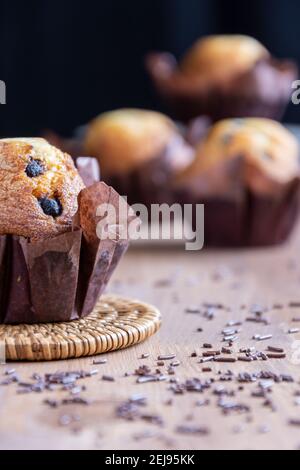 Nahaufnahme von Schokoladen-Muffins, selektiver Fokus, auf Holztisch, schwarzer Hintergrund, vertikal Stockfoto