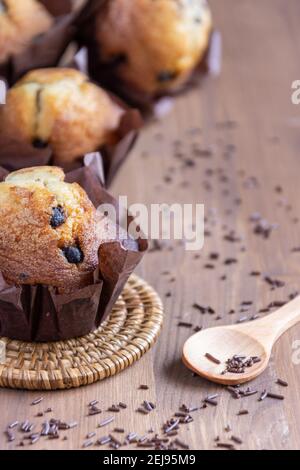 Draufsicht auf Schokoladen-Muffins, selektiver Fokus, Holzlöffel, Schokoladenspäne, auf Holztisch, Vertikal Stockfoto