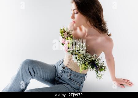 Junges Modell posiert mit Blumen in Bluse auf grauem Hintergrund Stockfoto