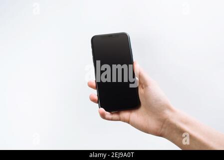 Samara Russland - 04,05.2020: Ein junger Mann klettert in ein Smartphone. Business Hand hält das schwarze Smartphone. Neueste Apple iPhone X oder 11, 12. Stockfoto