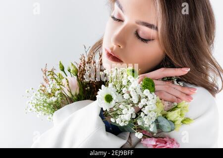 Frau posiert mit verschiedenen Blumen in Jacke isoliert auf grau Stockfoto