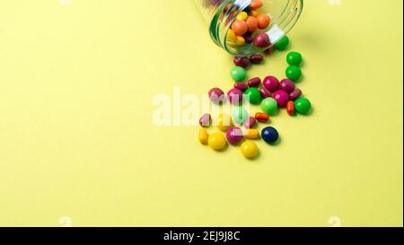 Bunte Süßigkeiten aus einem Glas auf einem farbigen gegossen Hintergrund Stockfoto