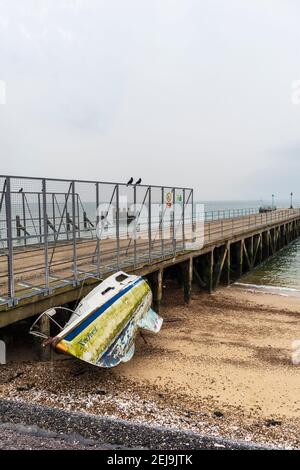 Verlassene Yacht 'Xanet' am Strand bei Shoeburyness Against Old verlassen Barge Pier Stockfoto