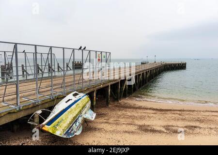 Verlassene Yacht 'Xanet' am Strand bei Shoeburyness Against Old verlassen Barge Pier Stockfoto