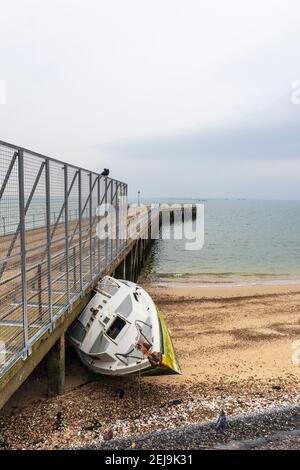 Verlassene Yacht 'Xanet' am Strand bei Shoeburyness Against Old verlassen Barge Pier Stockfoto