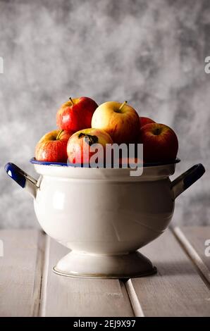 Rote Äpfel in antiker Terrine, auf weißem und grauem Hintergrund. Stockfoto