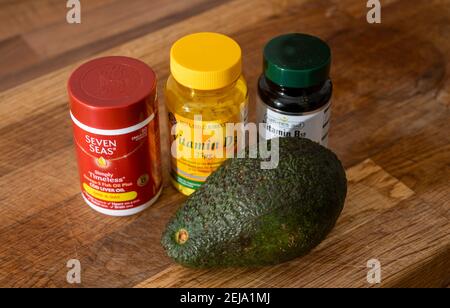 Verschiedene Flaschen Vitamintabletten und eine frische Avocadobirne Von M&S for Healthy living Lifestyle UK Stockfoto